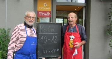 Harald und Herbert in Schürzen vor dem Café Möca