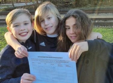 Drei Jungs mit Unterschriftenliste gegen Kinderarbeit