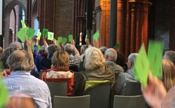 MV ind Kirche, Mitglieder halten grüne Abstimmungszettel hoch
