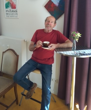 Herbert lehnt mit Cafe-Tasse in der Hand an Möca-Tisch