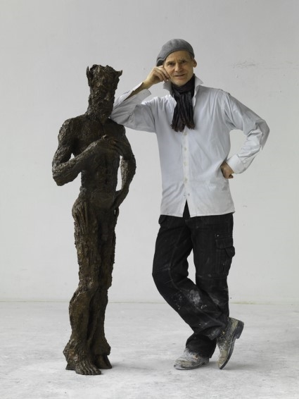Mann stützt sich auf fast gleichgroße männliche Skulptur